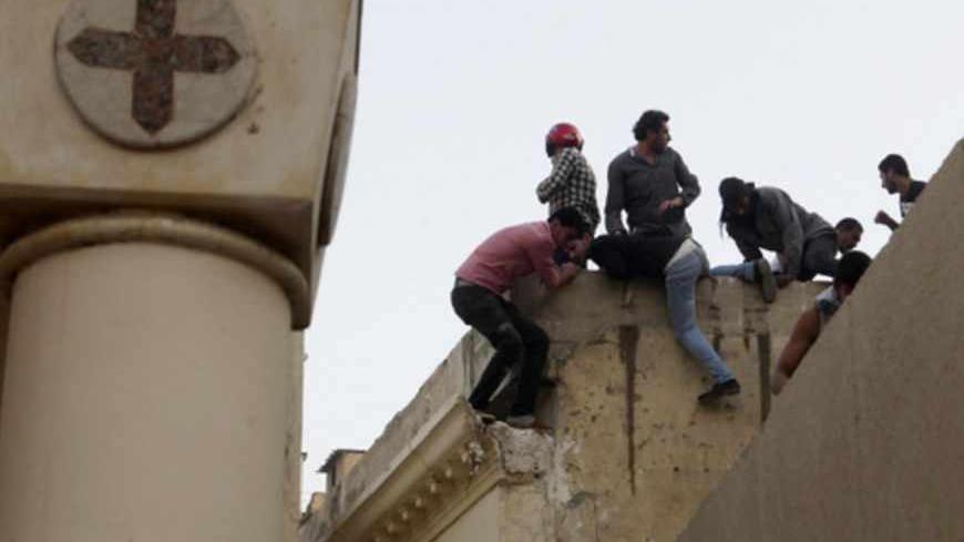 Coptic Christians run on the roof of the main cathedral in Cairo as police fire tear gas during clashes with Muslims standing outside the cathedral April 7, 2013. Clashes broke out between Coptic Christians and Muslims in central Cairo on Sunday after the funeral of four Copts killed in sectarian violence outside the Egyptian capital on Friday night, witnesses said.  REUTERS/Asmaa Waguih (EGYPT  - Tags: RELIGION CIVIL UNREST) - RTXYC7G
