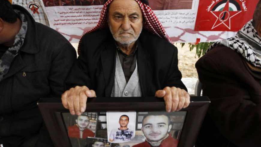 A Palestinian man holds photographs of his relative who is being held in an Israeli jail during a rally marking Prisoner Day in the West Bank city of Hebron April 17, 2013. "Prisoner Day," an annual commemoration of Palestinian prisoners, who currently number 4,800, was held on Wednesday, with Israeli security forces on standby for possible protests. REUTERS/Ammar Awad (WEST BANK - Tags: POLITICS) - RTXYOY3