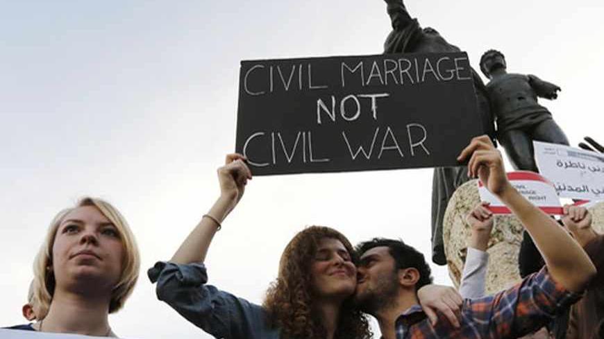 A man kisses a woman as they hold up a placard during a protest demanding to legalize civil marriage in Lebanon, at Martyrs' square in downtown Beirut February 4, 2013. Lebanese laws do not recognise civil marriages conducted in Lebanon. REUTERS/Jamal Saidi   (LEBANON - Tags: CIVIL UNREST) - RTR3DCHX