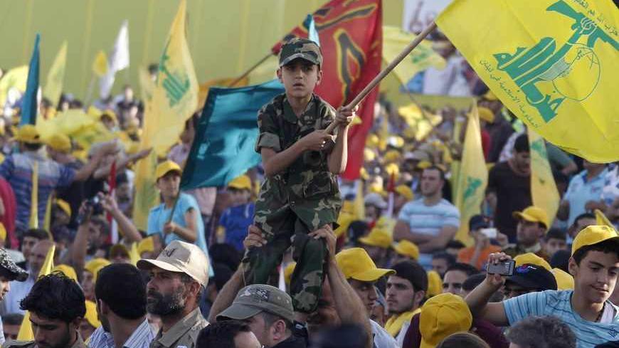 A boy wearing an army suit is held by people as they watch Lebanon's Hezbollah leader Sayyed Hassan Nasrallah as he appears on a screen during a live broadcast to speak to his supporters at an event marking Resistance and Liberation Day, in Bekaa valley May 25, 2013. The event is to commemorate the 13th anniversary of Israel's withdrawal from southern Lebanon. REUTERS/Sharif Karim (LEBANON - Tags: POLITICS) MEDIA ANNIVERSARY) - RTX100EC