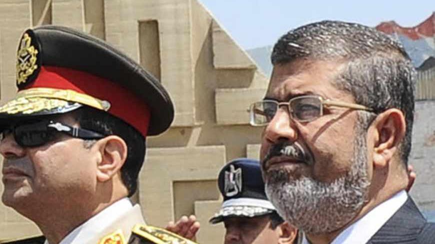 Egypt's President Mohamed Mursi (C) stands after laying a wreath during his visit to the tomb of former President Anwar al-Sadat and the Tomb of the Unknown Soldier during the commemoration of Sinai Liberation Day in Cairo April 24, 2013. Saluting next to Mursi are Egypt's Defence Minister Abdel Fattah al-Sisi (L) and General Sedki Sobhi (R), chief of staff to Egypt's Supreme Council of the Armed Forces (SCAF). Sinai Liberation Day is marked annually on April 25.   REUTERS/Egyptian Presidency/Handout (EGYPT
