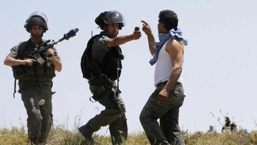 An Israeli border police officer aims pepper spray towards a Palestinian man during clashes between Jewish settlers and Palestinians in the West bank village of Urif, near Nablus April 30, 2013. The clashes erupted after an attack near Nablus. A Palestinian man stabbed and shot dead an Israeli settler in the occupied West Bank on Tuesday, the Israeli ambulance service and police said. REUTERS/Abed Omar Qusini (WEST BANK - Tags: POLITICS CIVIL UNREST TPX IMAGES OF THE DAY) - RTXZ4HJ