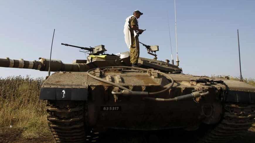 An Israeli soldier prays atop a tank close to the ceasefire line between Israel and Syria on the Israeli occupied Golan Heights May 6, 2013. Israel sought to persuade Syrian President Bashar al-Assad on Monday that its recent air strikes around Damascus did not aim to weaken him in the face of a more than two-year-old rebellion. REUTERS/Baz Ratner (ISRAEL - Tags: POLITICS MILITARY) - RTXZC70