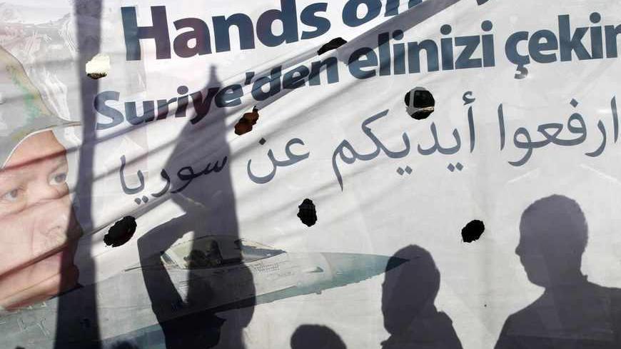 Shadows of protesters are cast on a banner as they march during a demonstration against the Turkish government's foreign policy on Syria, in central Hatay May 12, 2013. Turkey accused a group loyal to Syrian President Bashar al-Assad on Sunday of carrying out car bombings that killed 46 people in a Turkish border town and said the risk of unrest spreading to Syria's neighbours was increasing. Syrian Information Minister Omran Zubi denied any Syrian involvement and rejected what he called "unfounded accusati