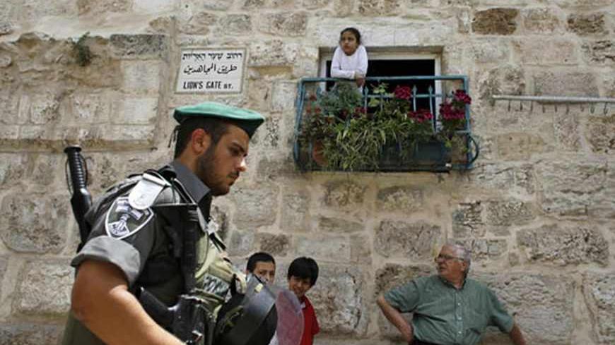 An Israeli border police officer walks past Palestinians in Jerusalem's Old City before a parade marking Jerusalem Day May 8, 2013. Jerusalem Day marks the anniversary of Israel's capture of the Eastern part of the city during the 1967 Middle East War. In 1980, Israel's parliament passed a law declaring united Jerusalem as the national capital, a move never recognised internationally. There were confrontations on Wednesday between Muslims and Jews outside Jerusalem's walled Old City, where al Aqsa mosque is