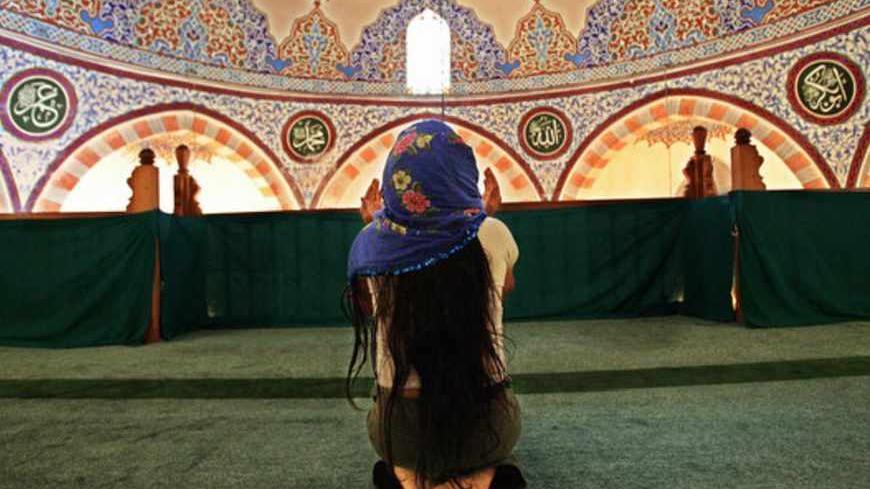 An Alevi woman prays in the women's part of the mosque in Hacibektash, 15 August 2005. The hamlet was named after Haci Bektas Veli, who lived between 1248 and 1337, founder of the Bektashi sect and of the Alevis -- an offshoot of Shiite Islam. He is revered as a manifestation of Ali, the last of the first four Caliphs and the son-in-law of the prophet Mohammed. Haci Bektas Veli, a humanist philospher, fled religious conflict in his native Central Asia, settled and lived and is buried here. The town of 8,000