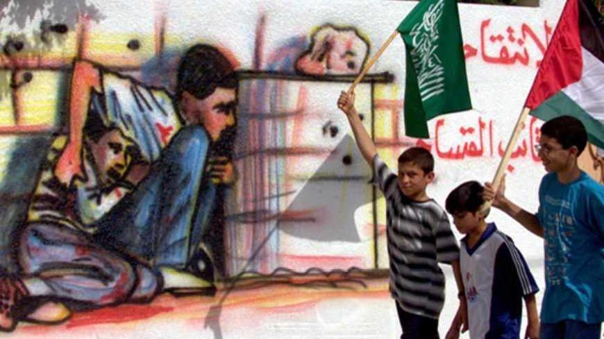 Palestinian boys carrying Hamas and Palestinian flags in the Gaza Strip October 6, 2000 as they walk past graffiti showing the death last Saturday of 12-year old Mohammad al-Durra, who was shot dead during Israeli-Palestinian clashes.  Israeli soldiers clashed with Palestinian stone-throwers on Friday in the West Bank and Gaza Strip where Islamic militants had declared a "Day of Rage".  Five Palestinians were shot dead on Friday, brionging the feath toll in nine days of violence to at least 74. - RTXK21I