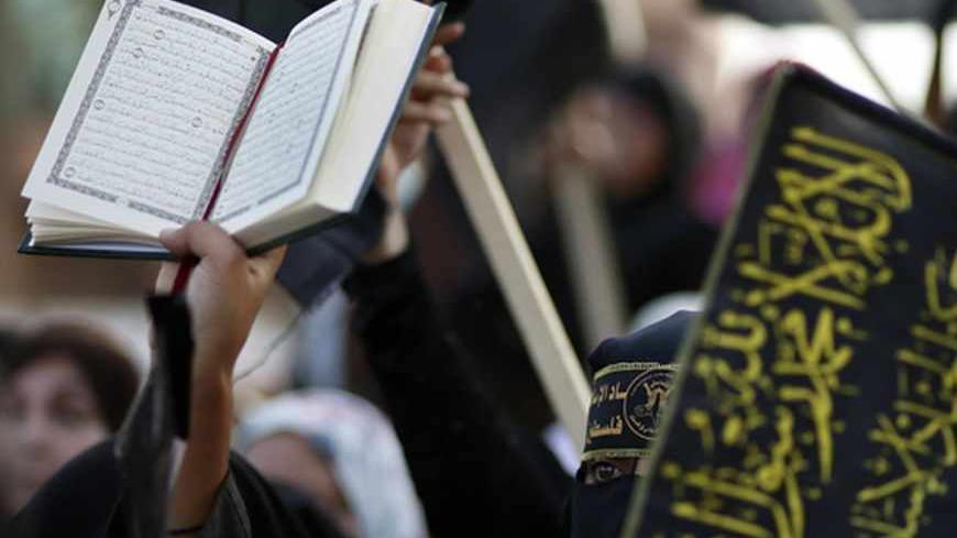 A woman holds a copy of Koran during a rally marking the 25th anniversary of foundation of the Islamic Jihad movement in Gaza City October 4, 2012. REUTERS/Suhaib Salem (GAZA - Tags: POLITICS CIVIL UNREST ANNIVERSARY RELIGION) - RTR38SLV