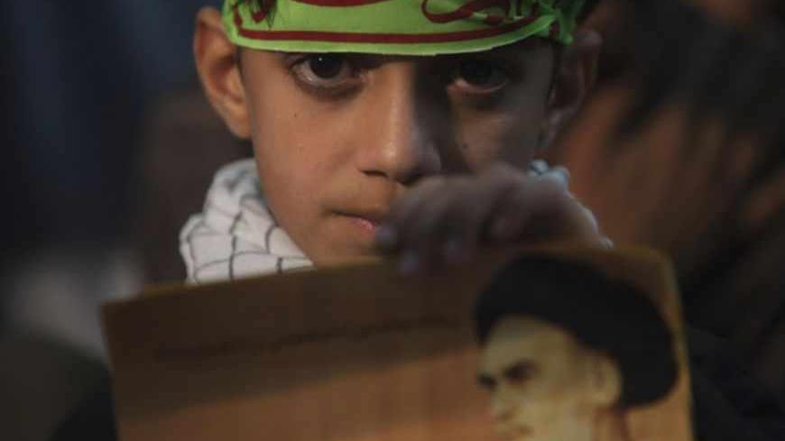 A youth holds a picture of Iran's late leader Ayatollah Ruhollah Khomeini during a ceremony to mark Khomeini's death anniversary at his tomb at Tehran's Behesht-Zahra cemetery June 3, 2011. REUTERS/Morteza Nikoubazl (IRAN - Tags: POLITICS ANNIVERSARY RELIGION) - RTR2N9KQ