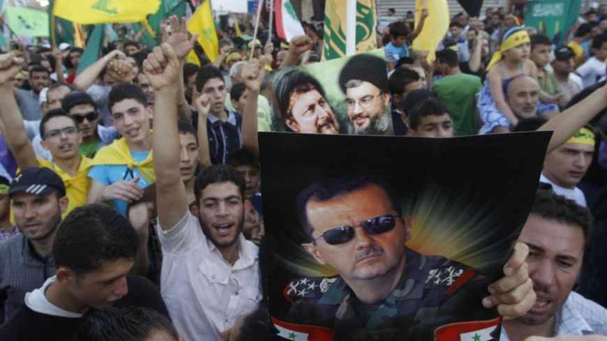 Supporters of Lebanon's Hezbollah leader Sayyed Hassan Nasrallah wave Hezbollah, Lebanese and Amal movement flags as one of them carries a poster depicting Syria's President Bashar al-Assad, at a protest against a film made in the United States that mocks the Prophet Mohammad, in Tyre, southern Lebanon September 19, 2012. REUTERS/Ali Hashisho  (LEBANON - Tags: POLITICS CIVIL UNREST RELIGION) - RTR385LT