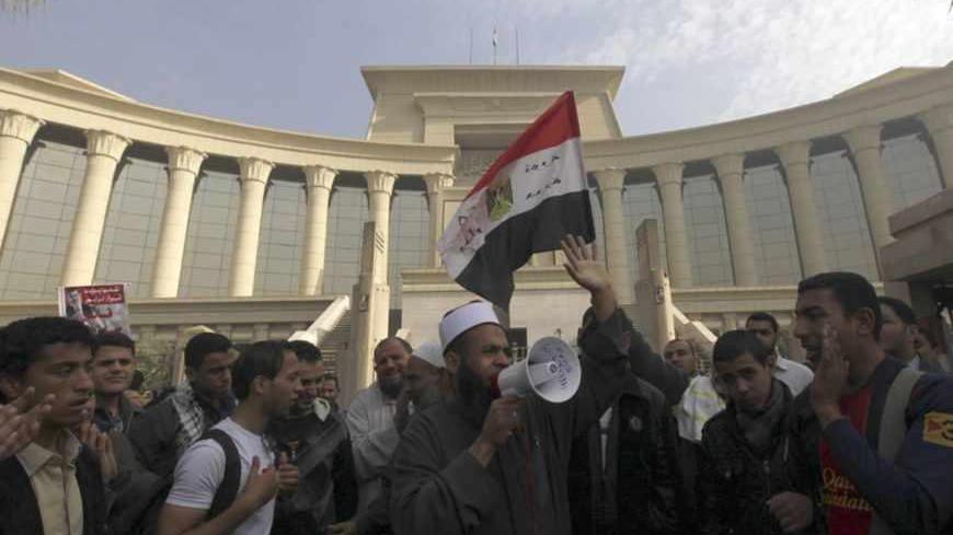 Supporters of Egyptian President Mohamed Mursi shout slogans and wave an Egyptian national flag in front of the Supreme Constitutional Court in Maadi, south of Cairo December 2, 2012. Egypt's Supreme Constitutional Court postponed its work indefinitely on Sunday after a protest by Islamists sympathetic to President Mohamed Mursi outside its headquarters. REUTERS/Amr Abdallah Dalsh  (EGYPT - Tags: POLITICS CIVIL UNREST CRIME LAW) - RTR3B4MT