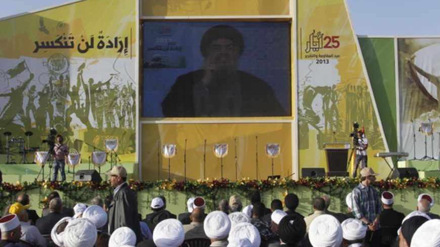 People watch Lebanon's Hezbollah leader Sayyed Hassan Nasrallah as he appears on a screen during a live broadcast to speak to his supporters at an event marking Resistance and Liberation Day, in Bekaa valley May 25, 2013. The leader of Lebanese guerilla movement Hezbollah said his group would stay in the Syrian war "to the end of the road" and bring victory to its ally President Bashar al-Assad. Hassan Nasrallah, head of the militant Shi'ite Muslim group, said in a televised speech on Saturday Syria and Leb