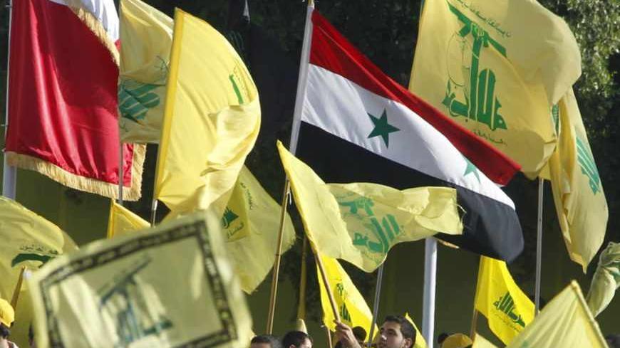 The Syrian flag is seen as people watch Lebanon's Hezbollah leader Sayyed Hassan Nasrallah as he appears on a screen during a live broadcast to speak to his supporters at an event marking Resistance and Liberation Day, in Bekaa valley May 25, 2013. The event is to commemorate the 13th anniversary of Israel's withdrawal from southern Lebanon. REUTERS/Sharif Karim (LEBANON - Tags: POLITICS ANNIVERSARY) - RTX100E4