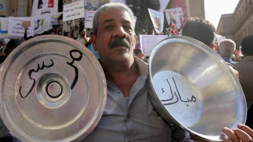 An anti-Mursi demonstrator holds pans reading, "Mubarak - Mursi" during a protest near the High Court in Cairo March 29, 2013. Anti-Mursi demonstrators marched the streets of downtown Cairo, protesting orders taken by prosecutor general, Talaat Ibrahim, to arrest five activists last week, a step the opposition decried as a reversal for democracy. REUTERS/Mohamed Abd El Ghany (EGYPT - Tags: POLITICS CIVIL UNREST) - RTXY287