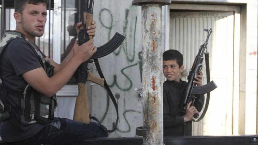 A Free Syrian Army fighter and a boy hold up weapons on a street at the Syrian town of Tel Abyad, near the border with Turkey, April 23, 2013. Picture taken April 23, 2013. REUTERS/Hamid Khatib (SYRIA - Tags: POLITICS CIVIL UNREST CONFLICT SOCIETY) - RTXYY7Q