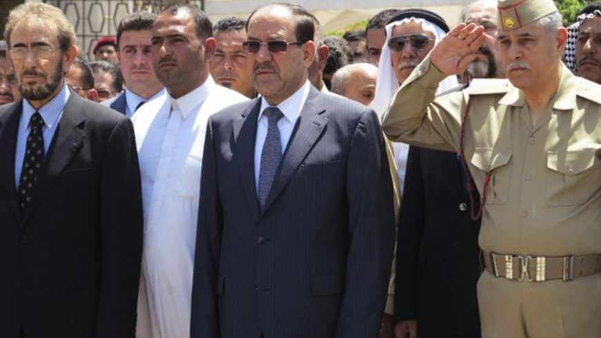 Iraq's Prime Minister Nuri al-Maliki (C) and acting Defence Minister Saadoun al-Dulaimi (L) attend a funeral ceremony for soldiers killed by militants, in Baghdad April 28, 2013. Militants shot dead five Iraqi soldiers in the Sunni Muslim stronghold province of Anbar on Saturday and protesters said they were forming an "army" after four days of unrest that raised fears of a return to widespread sectarian civil conflict. REUTERS/Stringer (IRAQ - Tags: POLITICS MILITARY CIVIL UNREST) - RTXZ2Y6