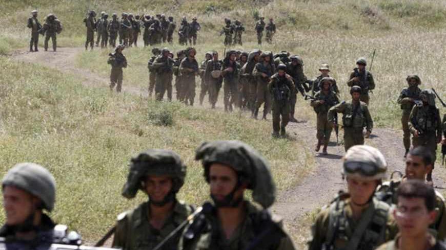 Israeli soldiers walk together during a training close to the ceasefire line between Israel and Syria on the Israeli occupied Golan Heights May 7, 2013. Israel played down weekend air strikes close to Damascus reported to have killed dozens of Syrian soldiers, saying they were not aimed at influencing its neighbour's civil war but only at stopping Iranian missiles reaching Lebanese Hezbollah militants. REUTERS/Baz Ratner (MILITARY POLITICS) - RTXZDG0