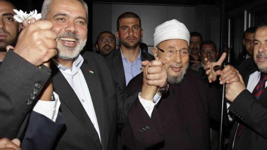 Hamas Prime Minister Ismail Haniyeh (L) holds the hand of Egyptian Cleric and chairman of the International Union of Muslim Scholars Sheikh Yusuf al-Qaradawi (R) upon al-Qaradawi's arrival at Rafah Crossing in the southern Gaza Strip May 8, 2013. Al-Qaradawi arrived on Wednesday for a three-day visit to Gaza Strip with a delegation of Muslim scholars. REUTERS/Ibraheem Abu Mustafa (GAZA - Tags: POLITICS RELIGION) - RTXZFCT