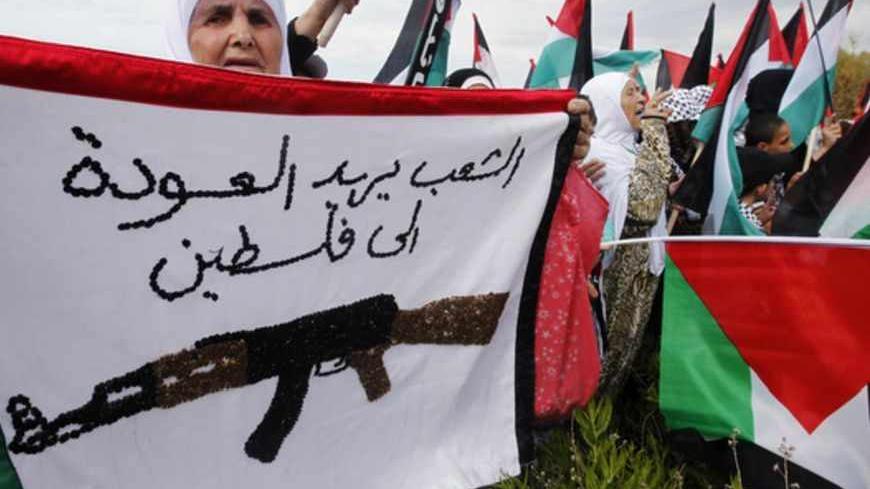 A Palestinian woman holds a banner bearing the colours of the Palestinian flag that reads, "The people want to return to Palestine", during a march to mark the 65th anniversary of Nakba near the United Nations Interim Force in Lebanon (UNIFIL) headquarters in the town of Naqoura, in southern Lebanon near the border between Lebanon and Israel, May 13, 2013. Palestinians will mark "Nakba" (Catastrophe) on May 15 to commemorate the expulsion or fleeing of hundreds of thousands of their brethren from their home