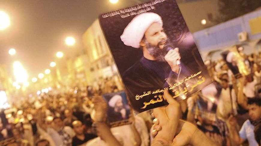 A protester holds up a picture of Sheikh Nimr al-Nimr during a rally at the coastal town of Qatif, against Sheikh Nimr's arrest July 8, 2012. Sheikh Nimr, a prominent Shi'ite Muslim cleric who was wanted by the police, was detained in Saudi Arabia's Eastern Province on Sunday over calls for more rights for the minority Muslim sect in the Sunni monarchy, his brother and an activist said. REUTERS/Stringer (SAUDI ARABIA - Tags: CIVIL UNREST RELIGION POLITICS) - RTR34QU9