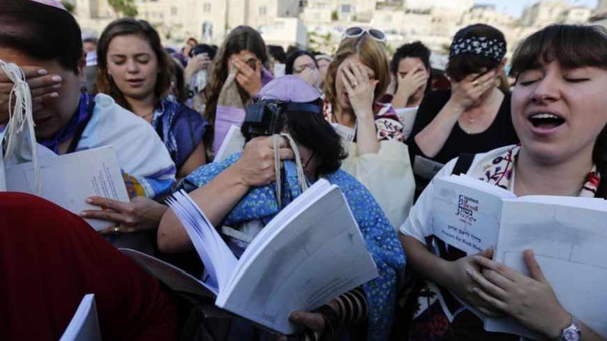 Members of "Women of the Wall" group wear prayer shawls and one (C) wearing Tefillin, leather straps and boxes containing sacred parchments, that Orthodox law says only men should don, during a monthly prayer session at the Western Wall in Jerusalem's Old City May 10, 2013. An Israeli police spokesman said on Friday that five ultra-Orthodox Jewish men were detained during a protest against the group. Last month the Jerusalem District Court said that the women should not be arrested for wearing prayer shawls