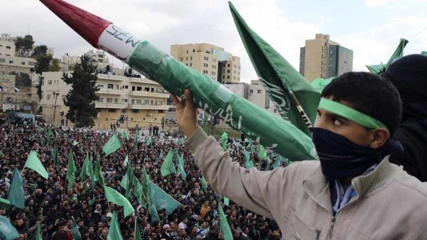 A Palestinian youth holds a model of a Hamas-made rocket during a rally in the West Bank city of Hebron, marking the 25th anniversary of the founding of Hamas, December 14, 2012. It was one of the first rallies Western-backed Palestinian President Mahmoud Abbas allowed to take place in the West Bank since 2007, when his Islamist rivals Hamas seized control of the Gaza Strip. REUTERS/Ammar Awad (WEST BANK - Tags: ANNIVERSARY CIVIL UNREST POLITICS) - RTR3BKFO