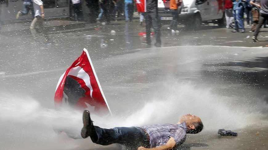 A man is hit by a jet of water as riot police use a water cannon to disperse demonstrators during a protest against Turkey's Prime Minister Tayyip Erdogan and his ruling Justice and Development Party (AKP) in central Ankara June 1, 2013. Erdogan made a defiant call for an end to the fiercest anti-government demonstrations in years on Saturday, as thousands of protesters clashed with riot police in Istanbul and Ankara for a second day.     REUTERS/Umit Bektas (TURKEY - Tags: POLITICS CIVIL UNREST TPX IMAGES 