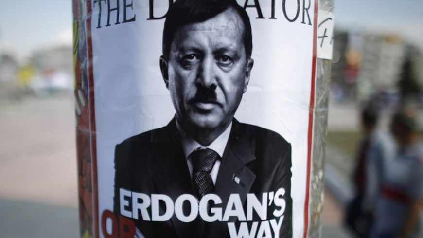 People walk past a poster depicting Turkish Prime Minister Tayyip Erdogan that has been pasted by demonstrators at Taksim Square in Istanbul June 5, 2013. Protesters clashed with police across Turkey overnight despite an apology for police violence from the deputy prime minister designed to halt an unprecedented wave of protest against Prime Minister Tayyip Erdogan. Pro-government newspapers signalled a softening of Ankara's line in the absence of Erdogan, who flew off on a state visit to north Africa on Mo