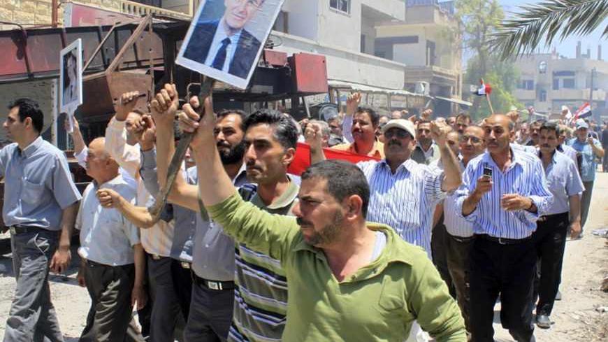 Civilians hold up pictures of Syria's President Bashar al-Assad and of his father, Syria's late president Hafez al-Assad (R), as they celebrate in Qusair June 6, 2013,  a day after the Syrian army took control of the town from rebel fighters. Syrian troops and Lebanese Hezbollah fighters pushed toward villages near Qusair on Thursday, a day after driving rebels from the border town shattered in weeks of combat. Insurgents seeking to overthrow Syrian President Bashar al-Assad were putting up a fierce fight a