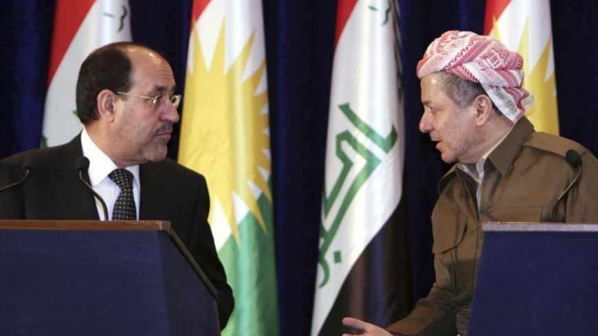 Iraqi Prime Minister Nuri al-Maliki (L) and Iraqi Kurdish President Masoud Barzani (R) speak to each other during a joint news conference in Arbil, about 350 km (220 miles) north of Baghdad June 9, 2013. Maliki visited the Kurdistan region on Sunday for the first time in more than two years, in an attempt to resolve a long-running dispute over oil and land that has strained Iraq's unity to the limit. REUTERS/Azad Lashkari (IRAQ - Tags: POLITICS) - RTX10HC4