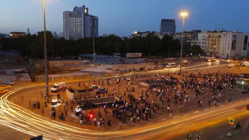 Cars drive pass people standing in silence during a protest at Taksim Square in Istanbul June 19, 2013. Turkey's deputy prime minister said on Wednesday he had no objection to silent anti-government protests inspired by a symbolic "Standing Man" vigil, comments that could help draw the sting out of three weeks of often violent demonstrations. REUTERS/Marko Djurica (TURKEY  - Tags: CIVIL UNREST POLITICS) - RTX10TVD