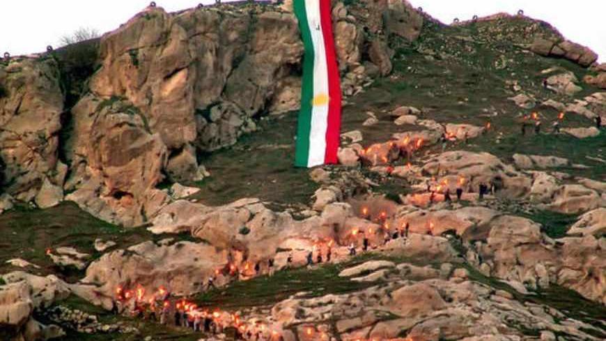 AKRA, Iraq:  Iraqi Kurds climb a mountain decorated with a huge Kurdish flag as they celebrate New Year or Newroz, 21 March 2006 in the northern town of Akra.  Iraq's predominantly Kurdish northern provinces celebrated New Year or Newroz with dancing and singing amid tight security as violence wracked the rest of the country. But traditional wishes for a happy new year took on additional urgency on the third anniversary of the US-led invasion of Iraq with the country teetering on the edge of civil war.     
