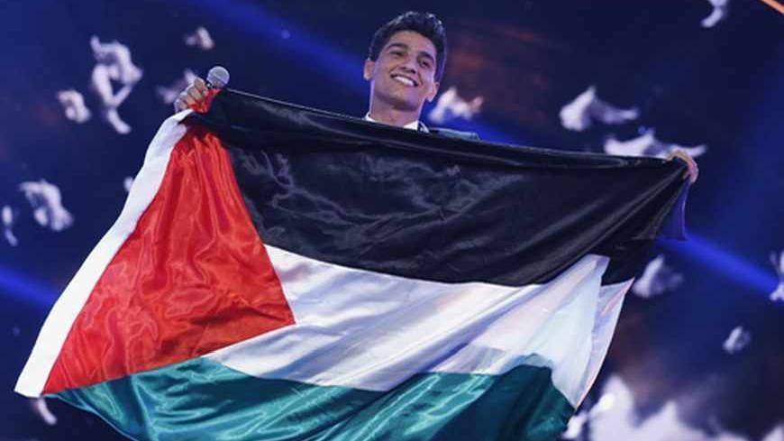 Palestinian singer Mohammed Assaf holds the Palestinian flag, as he stands on stage after being announced winner during the Season 2 finale of "Arab Idol" in Zouk Mosbeh area, north of Beirut June 22, 2013. REUTERS/Mohammed Azakir (LEBANON - Tags: ENTERTAINMENT TPX IMAGES OF THE DAY) - RTX10XJ4