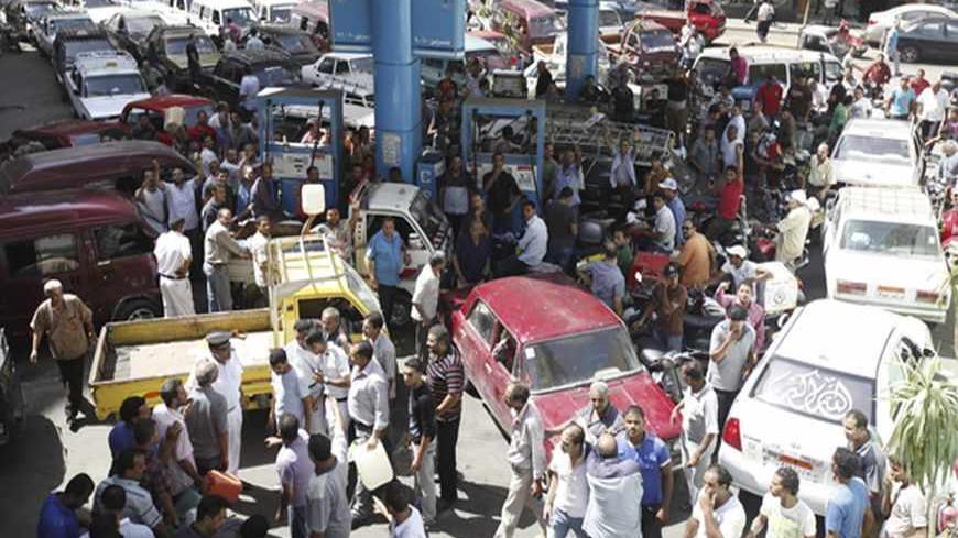 People crowd around a petrol station during a fuel shortage in Cairo June 26, 2013. President Mohamed Mursi will speak to the Egyptian people on Wednesday in a televised address that could determine his political survival as millions prepare to rally to demand his removal this weekend. Fears of a showdown in the streets between Mursi's Islamist supporters and a broad coalition of the disaffected have led people to stock up on food and buy up fuel supplies.   REUTERS/Mohamed Abd El Ghany (EGYPT - Tags: POLIT