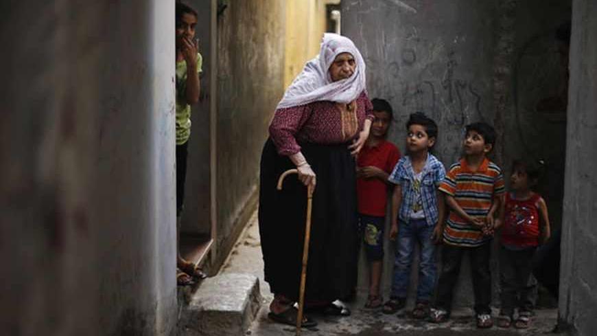 Palestinian refugee Fatem Redwan, 76, walks next to her grandchildren in the narrow alleys of Jabalya refugee camp at the northern Gaza Strip May 14, 2013. Redwan said she was 11 years old when she was forced out of her native town with her family to Gaza Strip. Palestinians will mark "Nakba" (Catastrophe) on May 15 to commemorate the expulsion or fleeing of some 700,000 Palestinians from their homes in the war that led to the founding of Israel in 1948.  REUTERS/Suhaib Salem (GAZA - Tags: CIVIL UNREST POLI