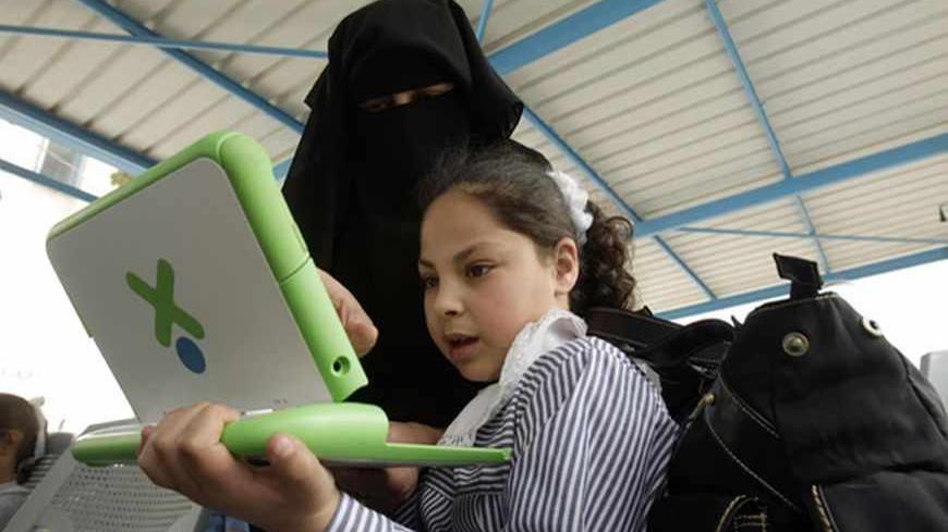 A teacher shows a Palestinian schoolgirl how to use a new laptop at a United Nations school in Rafah refugee camp in the southern Gaza Strip April 29, 2010. The United Nations Relief and Works Agency (UNRWA) launched a campaign to distribute some 200,000 laptops to UNRWA students in the Gaza Strip, an UNRWA official said. REUTERS/Ibraheem Abu Mustafa (GAZA - Tags: POLITICS EDUCATION) - RTR2D9BN