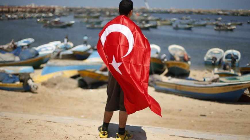 A Palestinian youth draped in a Turkish flag looks at the Gaza Seaport during a rally in support of Turkish Prime Minister Recep Tayyip Erdogan, in Gaza City June 18, 2013. REUTERS/Suhaib Salem (GAZA - Tags: POLITICS CIVIL UNREST) - RTX10RQ8