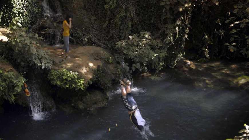 A resident jumps into water for a swim at Ahmed Awa tourist resort, known for its waterfalls, near Iraq's border with Iran where three American hikers are believed to have disappeared, near Sulaimaniyah, 260 km (160 miles) northeast of Baghdad, August 5, 2009.  An Iranian Foreign Ministry spokesman said on Wednesday he could not confirm whether three Americans had been detained by Iran. Picture taken August 5, 2009. REUTERS/Jamal Penjweny (IRAQ CONFLICT TRAVEL) - RTR26G8J