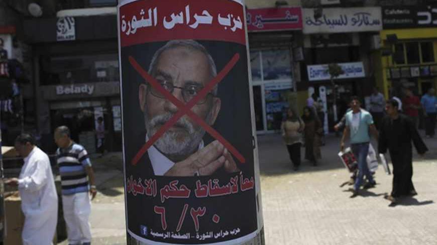 People walk past a defaced poster of Muslim Brotherhood leader Mohammed Badie with Arabic text which reads "Together to down brotherhood's power" near Tahrir Square in Cairo June 23, 2013.  REUTERS/Amr Abdallah Dalsh  (EGYPT - Tags: POLITICS CIVIL UNREST) - RTX10Y1J