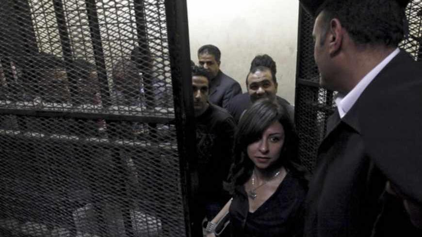 Activists, accused of working for unlicensed non-governmental organizations (NGOs) and receiving illegal foreign funds, stand in a cage during the opening of their trial in Cairo March 8, 2012. An Egyptian judge said on Thursday he was delaying until April 10 the trial of civil society activists including 16 Americans accused of receiving illegal foreign funds and pursuing their pro-democracy activities without a licence. REUTERS/Mohamed Abd El Ghany  (EGYPT - Tags: CIVIL UNREST POLITICS CRIME LAW) - RTR2Z1