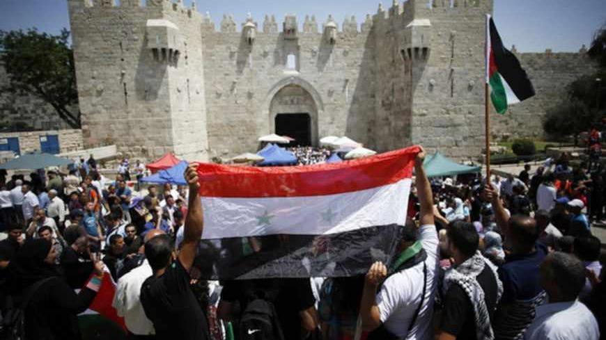 Palestinian protesters hold the Syrian national flag to show their support for Syrian President Bashar al-Assad during a demonstration outside Damascus Gate in Jerusalem's Old City June 7, 2013. A few dozen protesters took part in the demonstration after Friday prayers to mark the 46th anniversary of the 1967 Middle East war, when Israel captured East Jerusalem, the Gaza Strip, the West Bank and Golan Heights. REUTER/Baz Ratner (JERUSALEM - Tags: CIVIL UNREST POLITICS) - RTX10F5Y