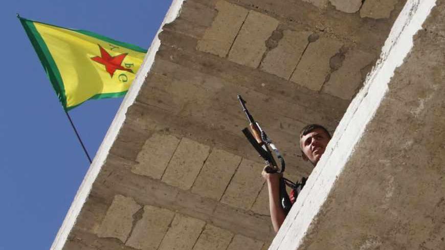 A Kurdish fighter from the Popular Protection Units (YPG) holds his weapon as he takes position atop a building with a YPG flag in Aleppo's Sheikh Maqsoud neighbourhood, June 7, 2013. Kurdish fighters from the YPG joined the Free Syrian Army to fight against forces loyal to Syria's President Bashar al-Assad. Picture taken June 7, 2013. REUTERS/Muzaffar Salman  (SYRIA - Tags: CIVIL UNREST POLITICS CONFLICT) - RTX10USX