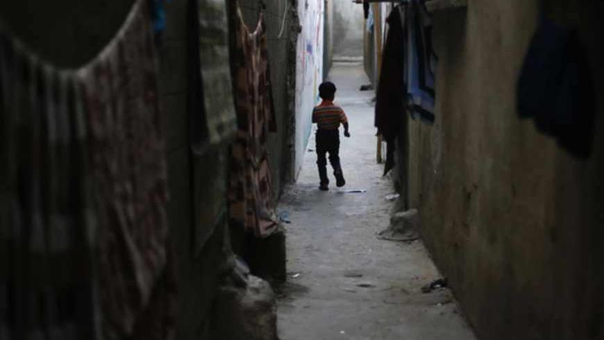 A Palestinian refugee boy walks between the narrow alleys of Jabalya refugee camp in the northern Gaza Strip May 14, 2013. Palestinians will mark "Nakba" (Catastrophe) on May 15 to commemorate the expulsion or fleeing of some 700,000 Palestinians from their homes in the war that led to the founding of Israel in 1948. REUTERS/Suhaib Salem (GAZA - Tags: CIVIL UNREST POLITICS) - RTXZM8H