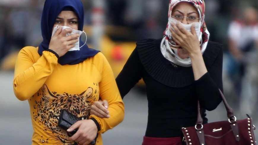 Women cover their faces as they try to avoid tear gas during protests at Kizilay square in central Ankara, June 16, 2013. The unrest, in which police fired teargas and water cannons at stone-throwing protesters night after night in cities including Istanbul and Ankara, left four people dead and about 5,000 injured, according to the Turkish Medical Association. REUTERS/Dado Ruvic (TURKEY - Tags: POLITICS CIVIL UNREST) - RTX10Q1T