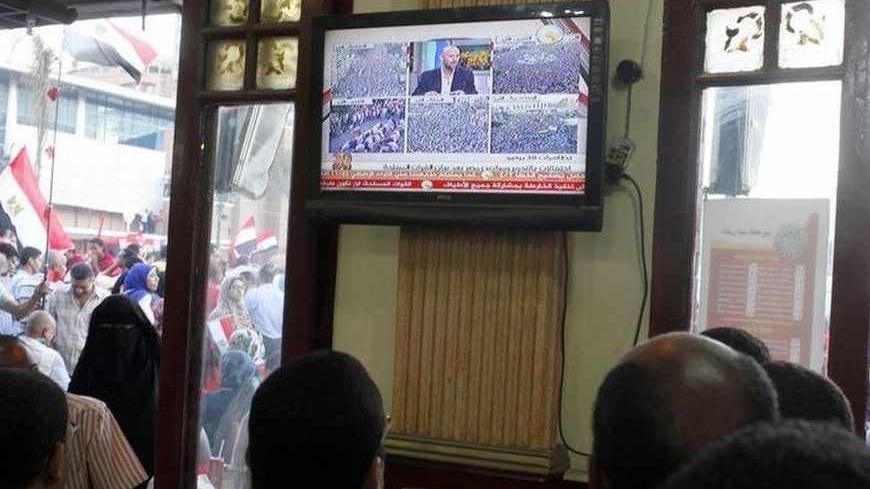 Anti-Mursi protesters follow the news on television in a public cafe on a main square where thousands gathered for a second day in Alexandria, July 1, 2013. Egypt's armed forces handed Islamist President Mohamed Mursi a virtual ultimatum to share power on Monday, giving feuding politicians 48 hours to compromise or have the army impose its own roadmap for the country.   REUTERS/Asmaa Waguih (EGYPT - Tags: POLITICS CIVIL UNREST) - RTX1198F