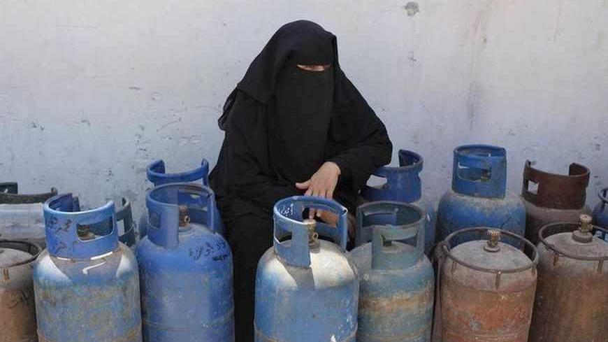 A Palestinian woman rests as she waits to fill her gas canisters at a gas filling station in Rafah in the southern Gaza Strip July 10, 2013. An Egyptian army crackdown launched months ago on the tunnel network has led to a severe fuel and gas crisis in the Gaza Strip. REUTERS/Ibraheem Abu Mustafa (GAZA - Tags: POLITICS) - RTX11IKG