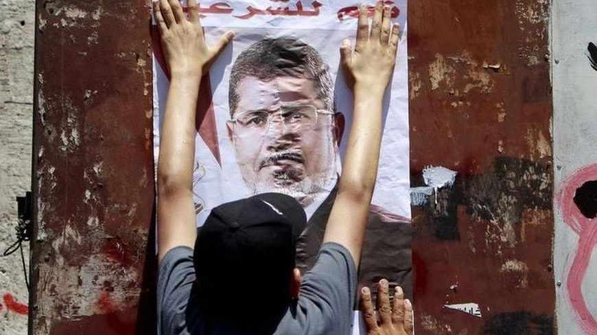 A supporter of deposed Egyptian President Mohamed Mursi hangs a poster of him on a wall during a march from the Al-Fath Mosque to the defence ministry, in Cairo July 30, 2013.    REUTERS/Mohamed Abd El Ghany (EGYPT  - Tags: POLITICS CIVIL UNREST) - RTX124W1