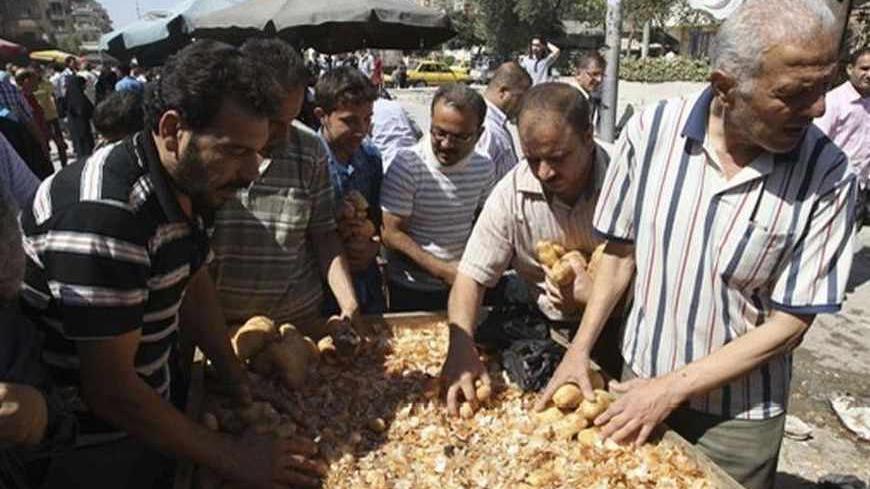 People buy potatoes from a street vendor on the first day of Ramadan, the holiest month in the Islamic calendar, at the Karaj Al-Hajez crossing, a passageway separating Aleppo's Bustan al-Qasr, which is under the rebels' control and Al-Masharqa neighborhood, an area controlled by the regime, July 10, 2013. REUTERS/Muzaffar Salman   (SYRIA - Tags: POLITICS CIVIL UNREST RELIGION) - RTX11J4H