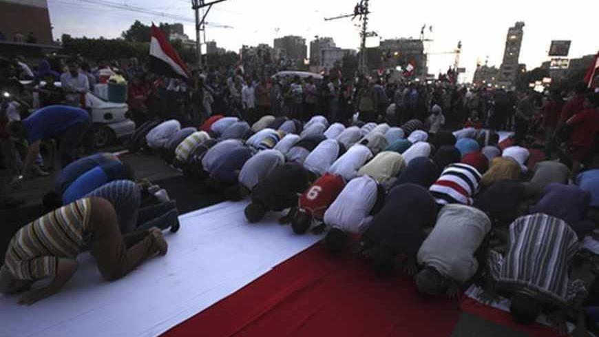Protesters opposing Egyptian President Mohamed Mursi kneel on an Egyptian flag during evening prayer at a protest against Mursi and members of the Muslim Brotherhood in front of the El-Thadiya presidential palace in Cairo July 1, 2013. Egypt's armed forces handed Mursi a virtual ultimatum to share power on Monday, giving feuding politicians 48 hours to compromise or have the army impose its own road map for the country. REUTERS/Amr Abdallah Dalsh  (EGYPT - Tags: POLITICS CIVIL UNREST) - RTX119H3