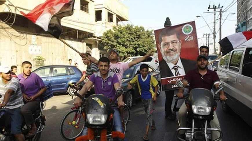 Palestinians celebrate in the streets in Gaza City after Islamist Mohamed Morsy of the Muslim Brotherhood (depicted in poster) was declared Egypt's first democratic president June 24, 2012. Morsy's win was hailed by Hamas, the Islamist group governing Gaza and which is locked in a power-struggle with the West Bank-based, U.S.-backed Palestinian Authority of President Mahmoud Abbas. REUTERS/Mohammed Salem (GAZA - Tags: POLITICS ELECTIONS) - RTR343GV